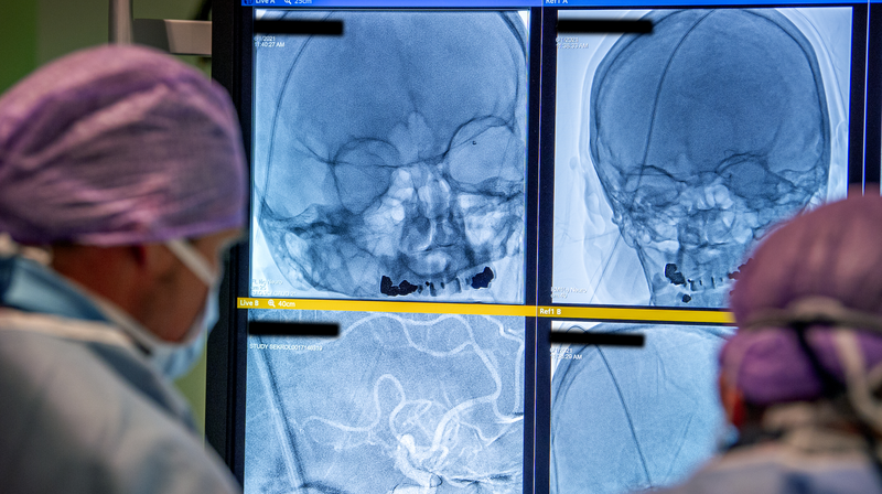 Första patienten. Teamet arbetar och i bakgrunden syns patientens röntgenbilder.