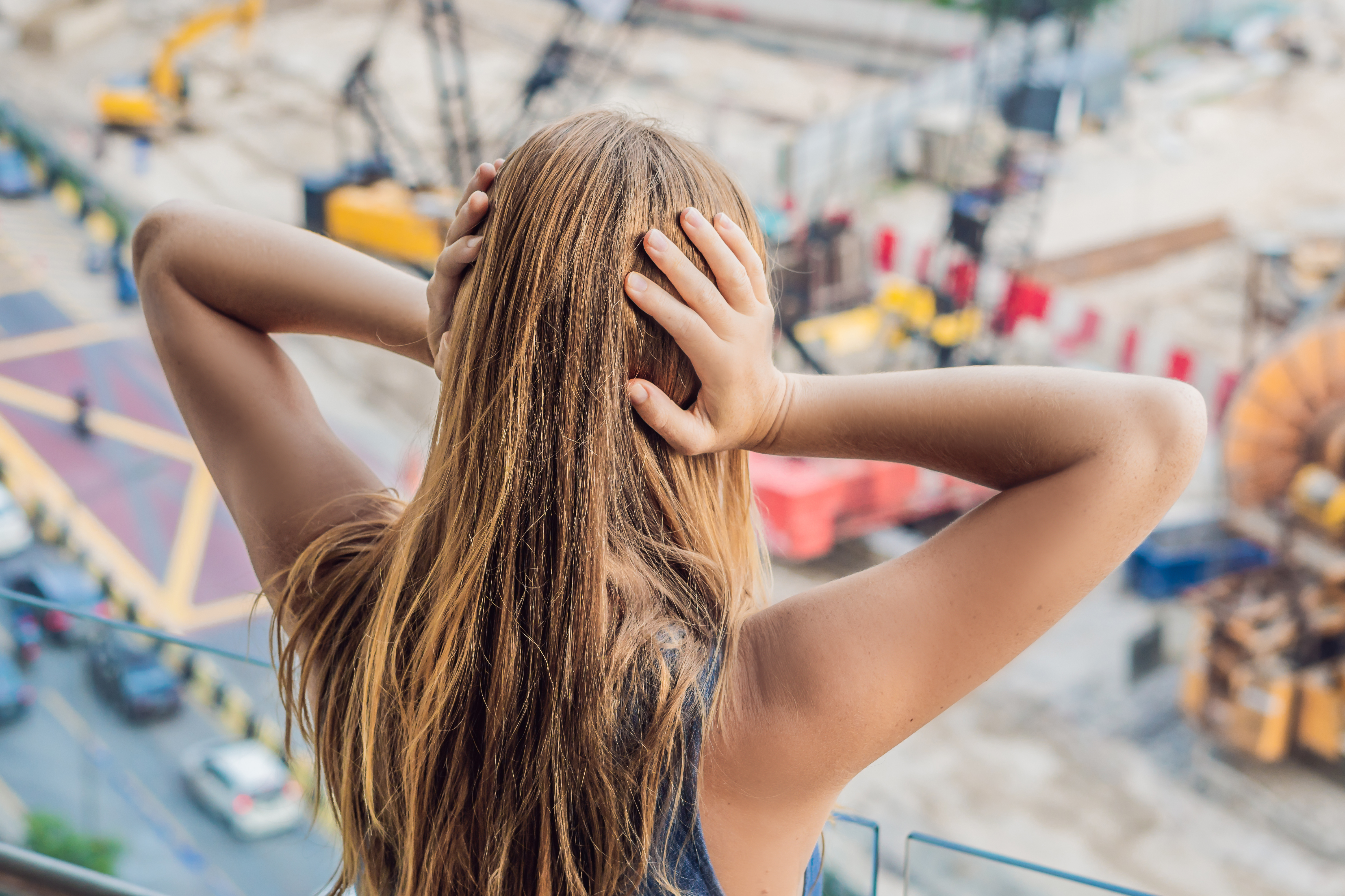 Kvinna som håller för öronen framför bullrig utomhusmiljö